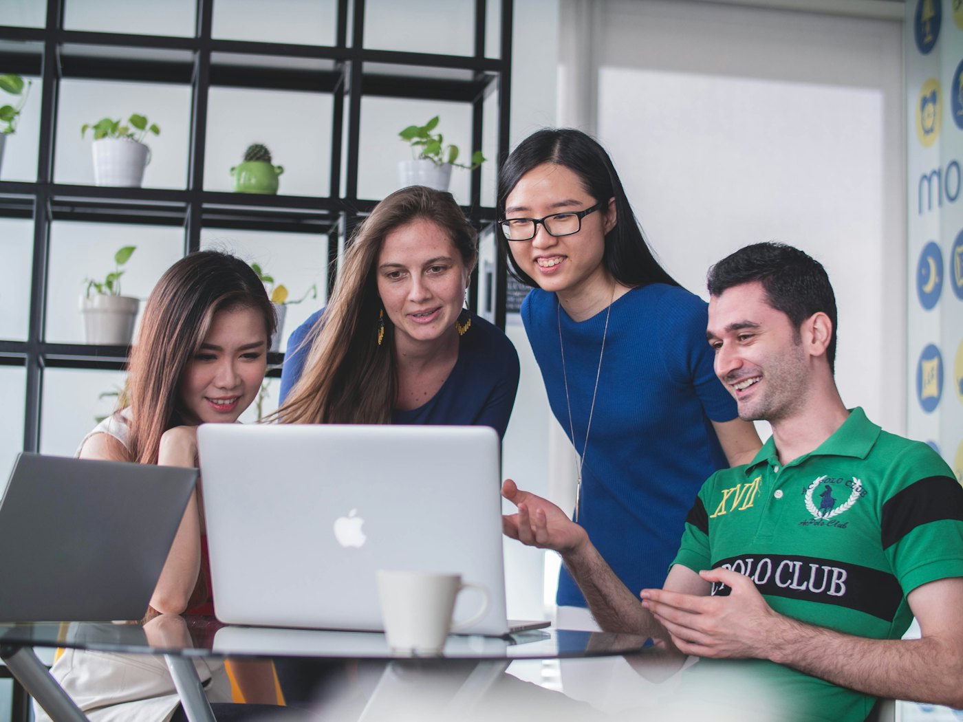 Students gathered around a laptop, smiling